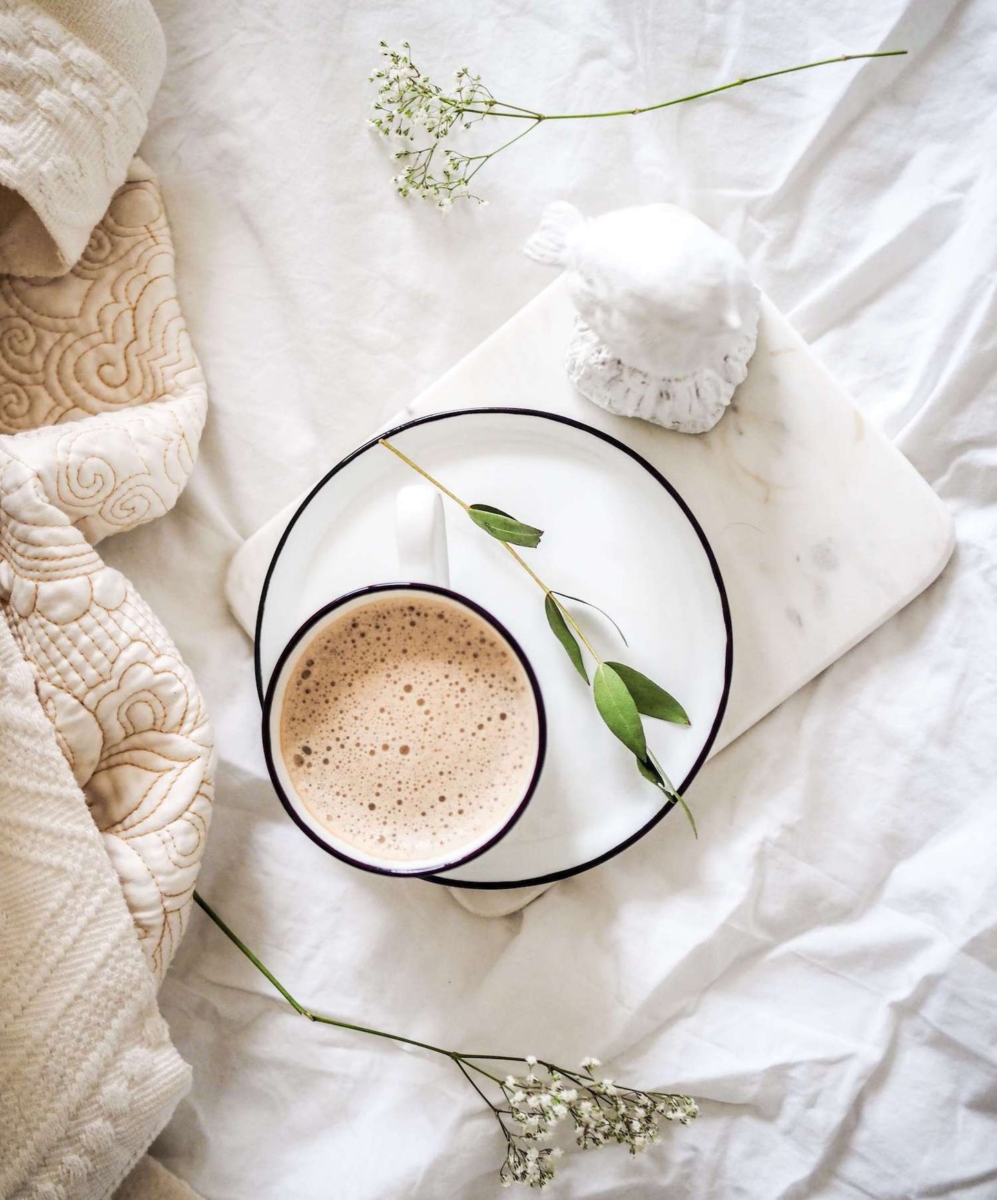 cup of hot cacao with baby's breath flowers on white linen